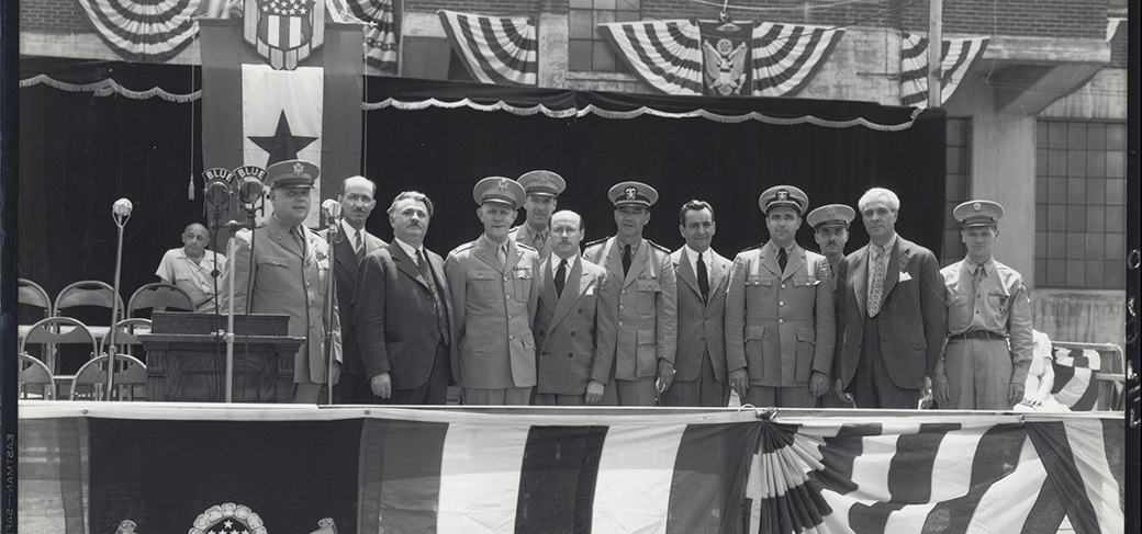 Chef Boyardee standing with World War II military leaders on a stage